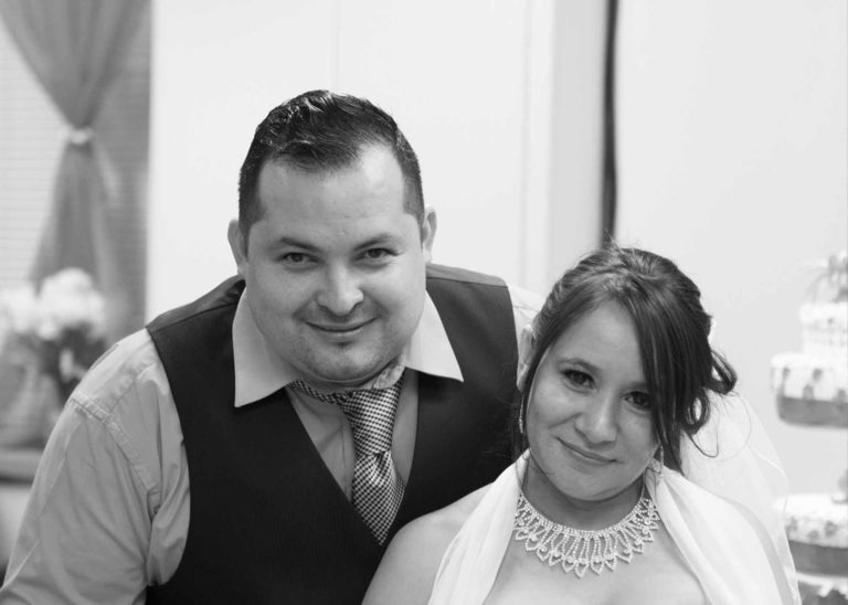 A monochrome photo of a Bride and Groom smiling at the camera on their Wedding Day