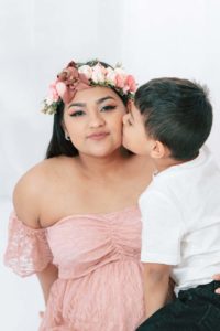 Smiling pregnant mother with smiling son kissing on the cheek