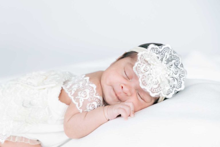 sleeping newborn girl in a white dress and flower head band