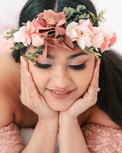 featured Smiling pregnant mother laying on the floor with a flower headband looking away