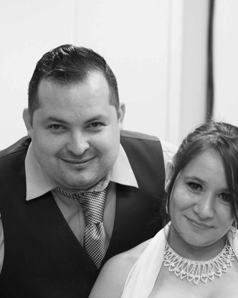 A monochrome photo of a Bride and Groom smiling at the camera on their Wedding Day