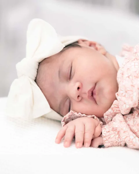 Newborn girl sleeping on a pillow with a beautiful headband